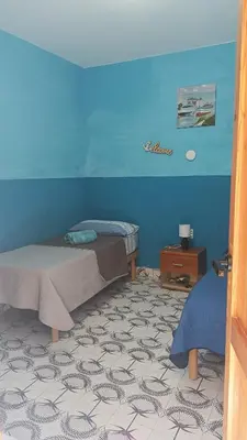 a room with two beds and a blue wall at LA TERRAZZA SUL MARE camera doppia vicino aereoporto&mare SICILIAN SEA STYLE ROOM in Cinisi