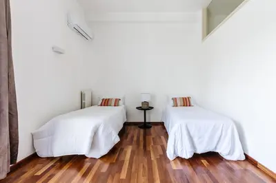 two beds in a room with white walls and wooden floors at Piazza Marina Suite By DomuSicily in Palermo