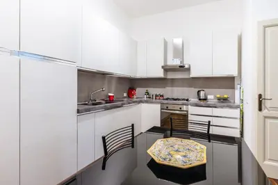 a kitchen with white cabinets and a table and chairs at Piazza Marina Suite By DomuSicily in Palermo
