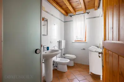 a bathroom with a white toilet and a sink at La Gurra Tenuta Migliore By DomuSicily in Chiusa Sclafani