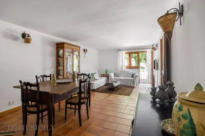a dining room with a table and a living room at La Gurra Tenuta Migliore By DomuSicily in Chiusa Sclafani