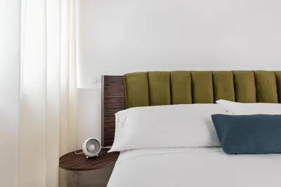 a bedroom with a white bed with a green headboard at La Terrazza su Dante Rooms in Palermo