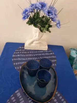 a table with blue bowls and a vase with blue flowers at Onda blu in Carini