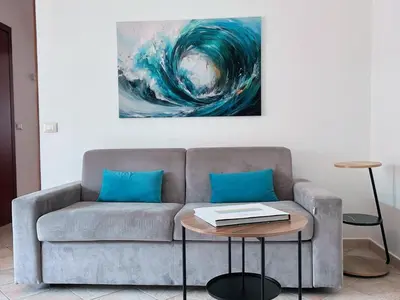 a living room with a couch and a painting of a wave at D'Amelio Sweet Home in Palermo