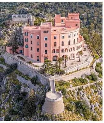a large pink building with palm trees in front of it at D'Amelio Sweet Home in Palermo