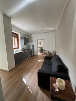 a living room with a black couch and a kitchen at LaPignaVerde in Palermo