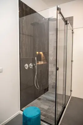 a glass shower with a blue stool in a bathroom at Casa Degli Aragonesi in Palermo
