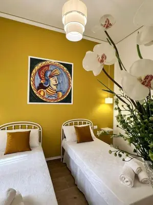 two beds in a room with yellow walls and flowers at Casa Vacanze Tirreno in Trabia