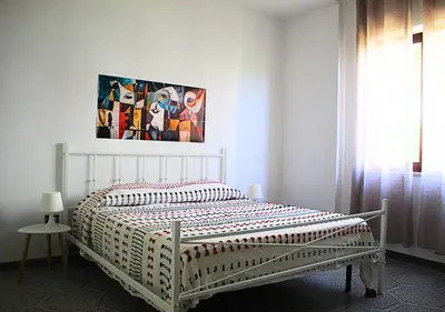 a white bed in a bedroom with a painting on the wall at Villa Giorgia in Alcamo
