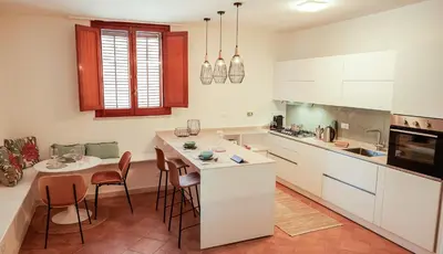a kitchen with white cabinets and a table and chairs at Villa Regina ai Faraglioni di Scopello in Scopello