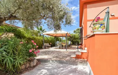 a patio with an umbrella next to a building at Amazing Home In Castellammare Del Golf in Castellammare del Golfo