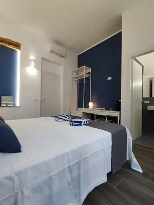 a bedroom with a large white bed with blue walls at Donna Oliva Guest House in Palermo