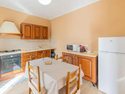 a kitchen with a white table and a refrigerator at Casa Vacanze La Dolce Vita in Mandra Capreria