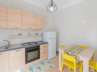 a kitchen with a table and a white refrigerator at Casa Vacanze Ginevra in Mandra Capreria