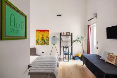 a white living room with a couch and a tv at Azizò, la Verde in Palermo