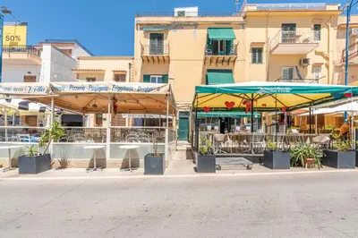 two stores with umbrellas in front of a building at Casetta al Molo di Mondello by Wonderful Italy in Palermo