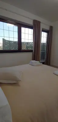 a bedroom with a large white bed with two windows at Villa due Scale in Palermo
