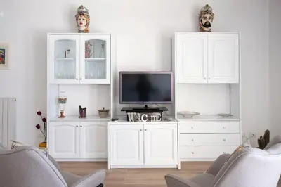 a living room with a tv and white cabinets at Villa due Scale in Palermo