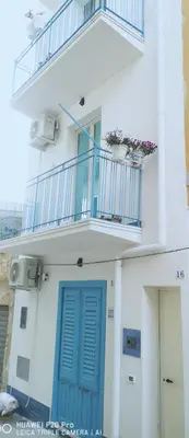 a white building with a blue door and a balcony at Casa di via Sole in Castellammare del Golfo