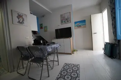 a room with a table and chairs and a television at Casa di via Sole in Castellammare del Golfo