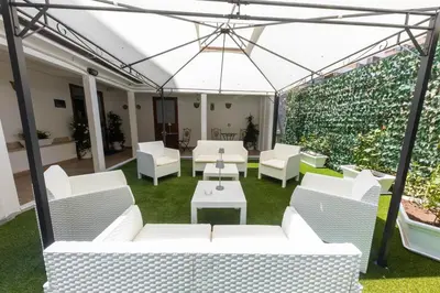 a patio with white furniture and a green hedge at I RE di SICILIA 2 in Palermo