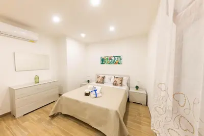 a white bedroom with two beds and a tv at I RE di SICILIA 2 in Palermo