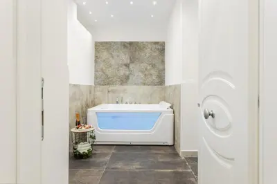 a bathroom with a tub and a washing machine at Aragona House in Palermo