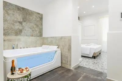 a white bathroom with a tub and a bed at Aragona House in Palermo