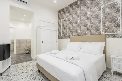 a bedroom with a large white bed and a tv at Aragona House in Palermo