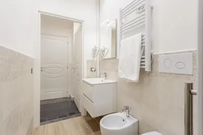 a white bathroom with a sink and a toilet at Aragona House in Palermo