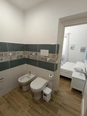 a bathroom with a toilet and a sink and a bed at Balarm Central Apartment in Palermo