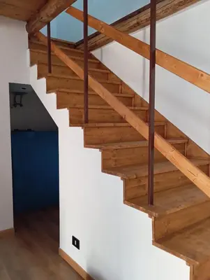 a wooden staircase in a loft with wooden beams at B&b da Ely in Ventimiglia di Sicilia
