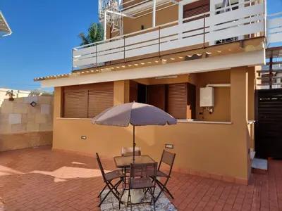 a table with an umbrella in front of a building at Vida Loca -Appartamento vicino aereporto e 200mt spiaggia in Carini
