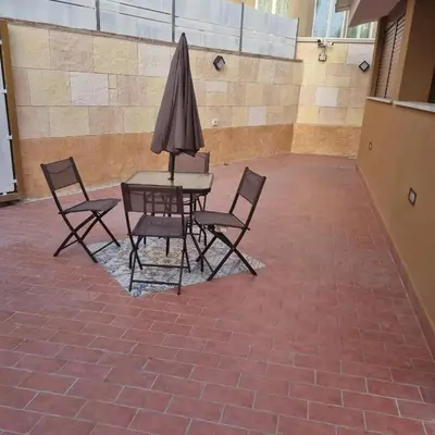 a table with chairs and an umbrella on a brick floor at Vida Loca -Appartamento vicino aereporto e 200mt spiaggia in Carini