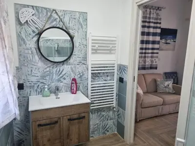 a bathroom with a sink and a mirror and a couch at Vida Loca -Appartamento vicino aereporto e 200mt spiaggia in Carini