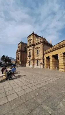 an old building with people sitting in front of it at Pietro Fudduni Apartment in Palermo