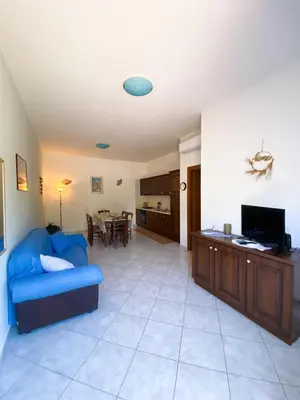 a living room with a blue couch and a kitchen at Sole di Sicilia in Castelluzzo
