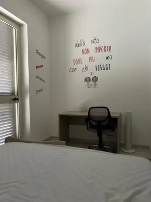 a bedroom with a bed and a chair and writing on the wall at Casa Maria Grazia Villa indipendente con vista mozzafiato a Monreale in Monreale