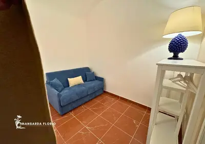 a blue couch sitting next to a table with a lamp at Mansarda Florio in Palermo