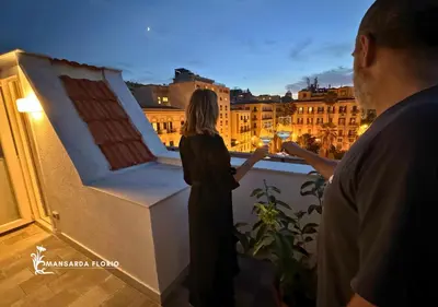 a woman standing on a balcony looking out at the city at Mansarda Florio in Palermo