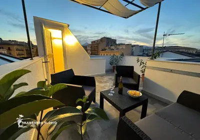 a balcony with a table and chairs on a roof at Mansarda Florio in Palermo