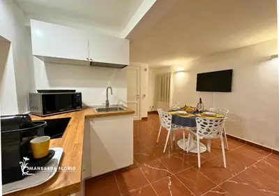 a kitchen with a table and chairs in a room at Mansarda Florio in Palermo