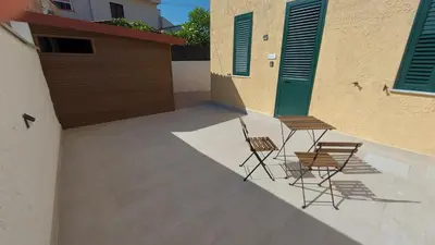 two chairs and a table on a patio next to a building at Mondello House in Palermo
