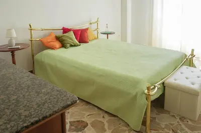 a bedroom with a bed with a green comforter at Dolce Sicily a 2km dal centro in Palermo