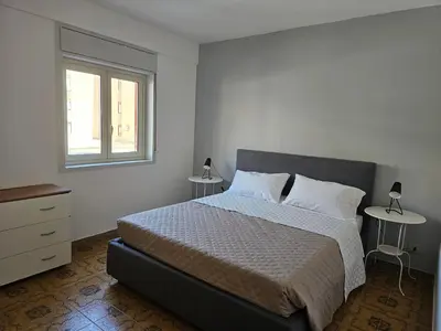 a bedroom with a bed with two tables and a window at Guests's Nest in Castellammare del Golfo