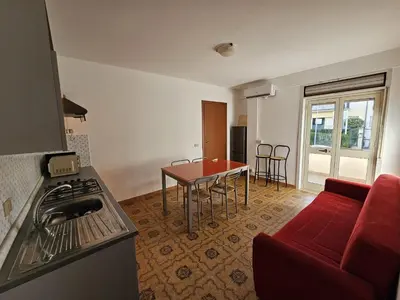 a living room with a red couch and a table at Guests's Nest in Castellammare del Golfo