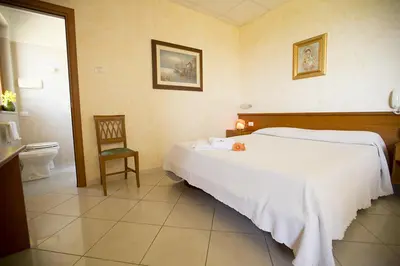 a bedroom with a white bed and a toilet at Albergo La Principessa in Alcamo