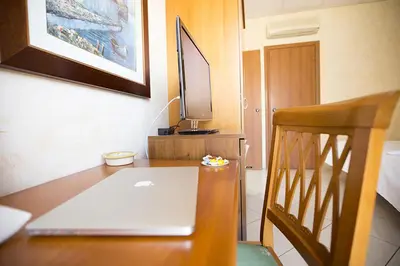 a laptop computer sitting on a wooden desk with a tv at Albergo La Principessa in Alcamo