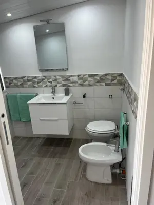 a white bathroom with a toilet and a sink at Casa vacanze Giada in Terrasini