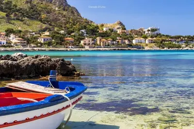 a boat sitting on the beach next to the water at Casa vacanze Casuzza Sferracavallo Palermo in Palermo
